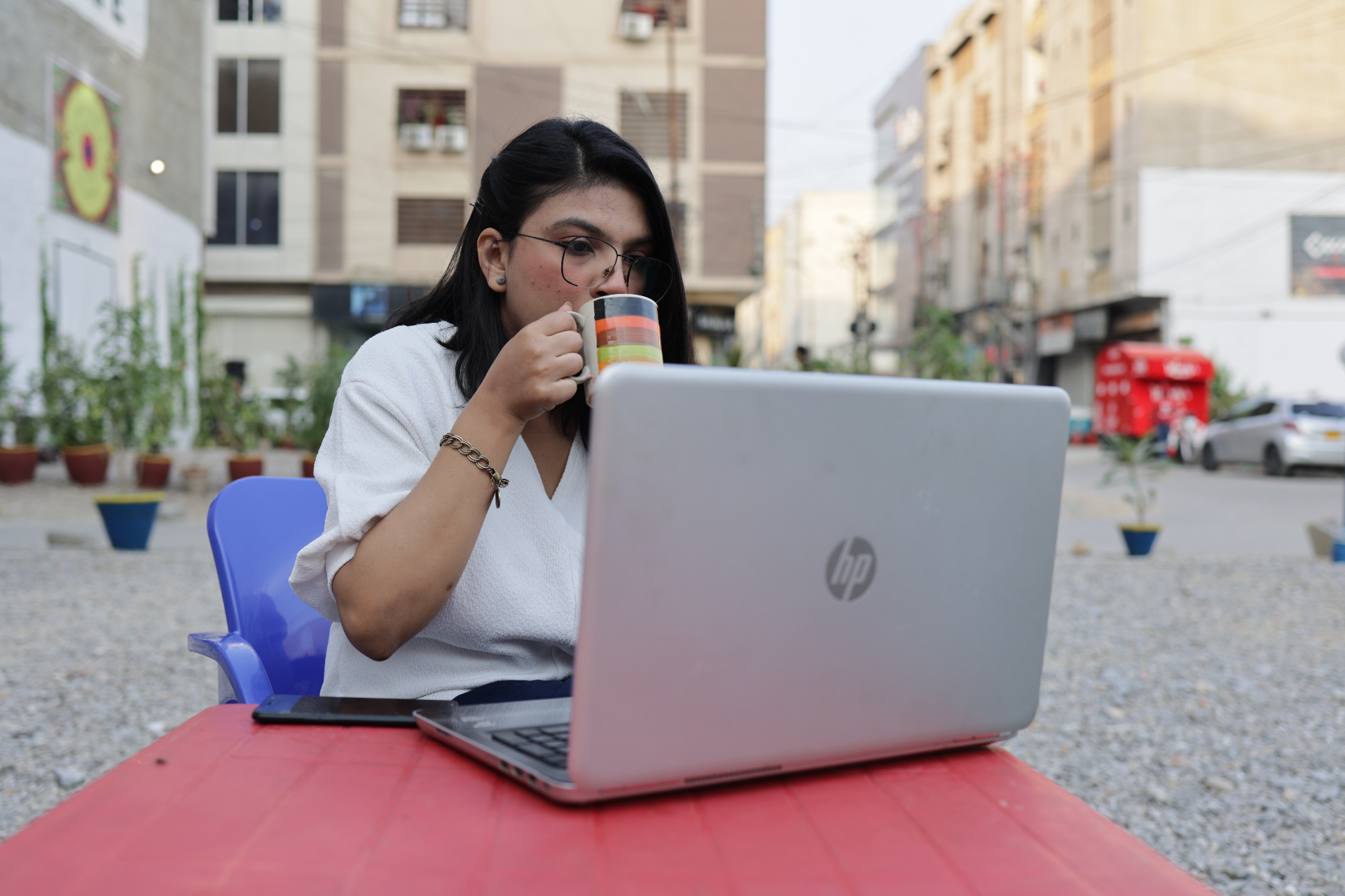 A communications manager leaning forward at her laptop in a warm office, gesturing at a clearly visible story library with sentiment-coded story cards and data points, a printed proposal and handwritten notebook on the desk