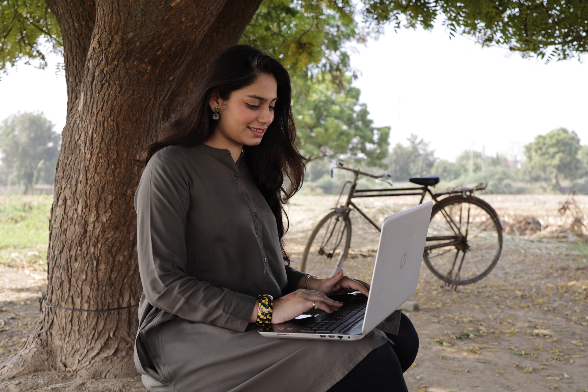 An open printed impact report on a warm wooden desk beside a laptop with a draft document, surrounded by pages of charts and pull quotes